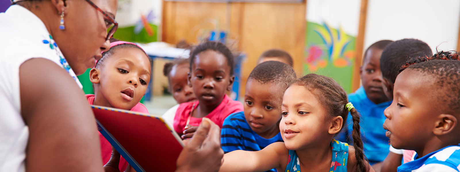 elementary children interacting and engaged with teacher who is showing a book to them