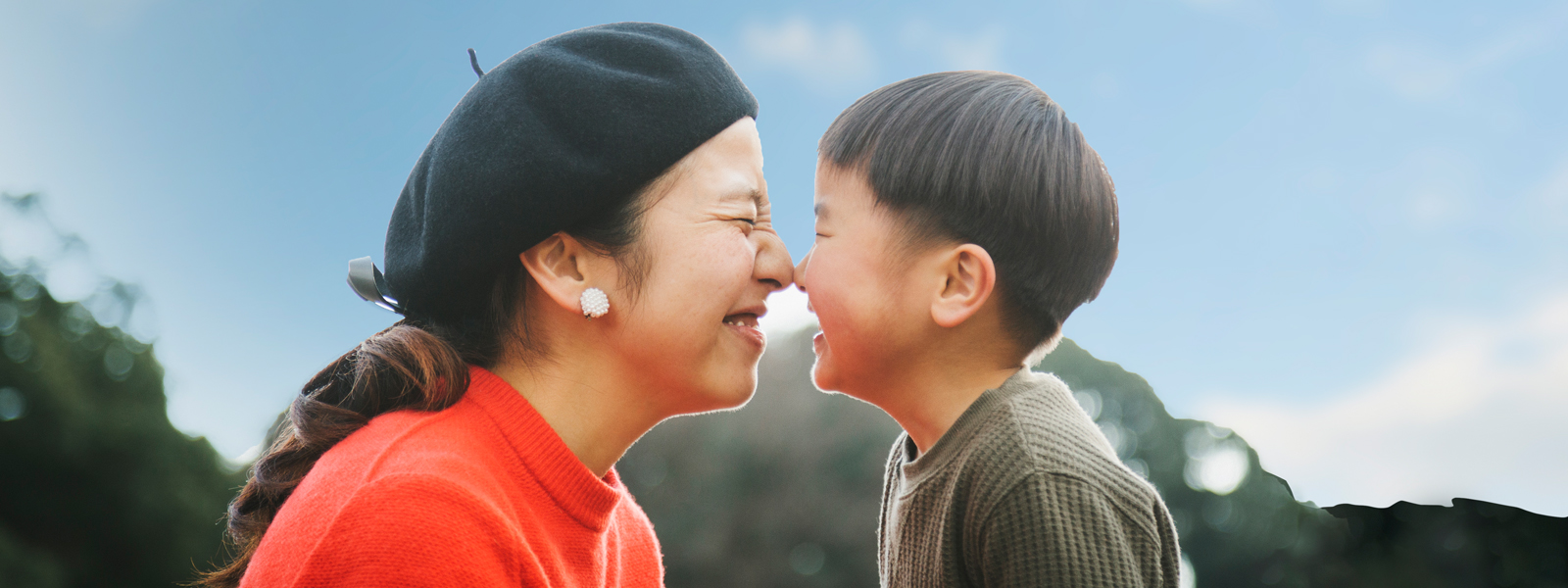 Mom and child laughing with scrunched up faces while touching noses.